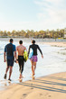 © David Mitchell/Caia Image - Male surfers walking with surfboards on sunny ocean beach