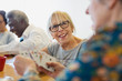 © Martin Barraud/Caia Image - Smiling senior woman playing cards with friend in community center