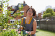 © Sam Edwards/Caia Image - Portrait smiling woman gardening in sunny yard