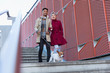 © Chris Ryan/Caia Image - Smiling young couple walking dog down urban, modern stairs
