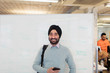 © Sam Edwards/Caia Image - Portrait smiling, confident Indian businessman in turban standing at whiteboard in office