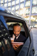 © Paul Bradbury/Caia Image - Businessman drinking coffee, using digital tablet in crowdsourced taxi