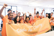 © Sam Edwards/Caia Image - Portrait enthusiastic hackers cheering banner, coding for charity at hackathon