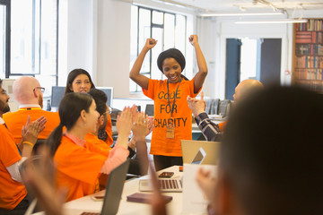 Happy hackers cheering for woman, coding for charity at hackathon