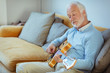 © Robert Daly/Caia Image - Active senior man playing guitar on living room sofa