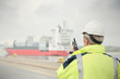 © Rafal Rodzoch/Caia Image - Dock manager with walkie-talkie watching container ship at commercial dock