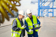 © Agnieszka Olek/Caia Image - Dock workers with walkie-talkie and clipboard meeting at shipyard