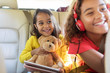 © Sam Edwards/Caia Image - Happy sisters with teddy bear riding in back seat of car