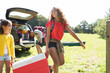 © Sam Edwards/Caia Image - Sisters camping, carrying cooler in sunny field