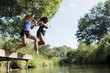 © Sam Edwards/Caia Image - Carefree mother and daughter jumping into river
