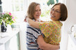 © Tom Merton/Caia Image - Portrait affectionate senior lesbian couple hugging in kitchen