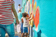© Trevor Adeline/Caia Image - Girl volunteer painting vibrant mural on sunny wall