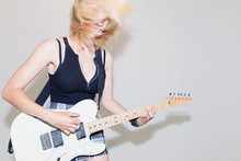 Exuberant Young Woman Playing Electric Guitar