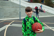 © Paul Bradbury/Caia Image - Portrait confident tween boy with basketball in schoolyard
