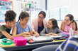 © Robert Daly/Caia Image - Female teacher junior high school girl students studying at desk in classroom