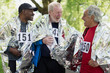 © Robert Daly/Caia Image - Active senior men friends finishing sports race, wrapped in thermal blankets