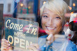 © Tom Merton/Caia Image - Portrait confident young female shop owner holding Open sign at window