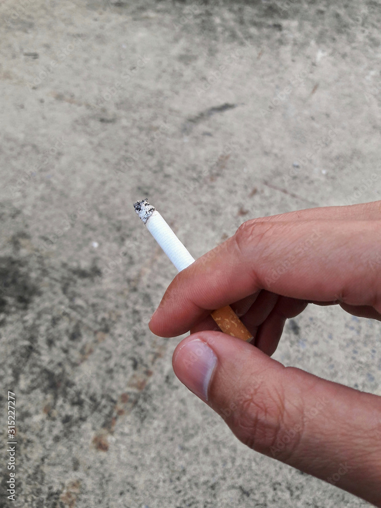 cigarette real Cigarette pick by hand with concrete background. Stock Photo