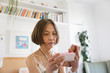 © Tom Merton/Caia Image - Senior woman with smart phone looking at box of medicine