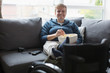 © Martin Barraud/Caia Image - Smiling young woman watching TV eating popcorn on sofa feet up on wheelchair