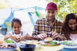 © Sam Edwards/Caia Image - Father and daughters enjoying hamburger lunch at campsite