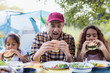 © Sam Edwards/Caia Image - Father and daughters eating barbecue hamburgers at campsite