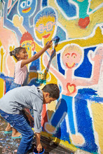 Children Painting Vibrant Mural On Sunny Wall