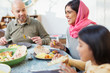 © Robert Daly/Caia Image - Happy woman in hijab eating dinner with family at table