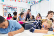 © Robert Daly/Caia Image - Female teacher helping junior high school girl students doing homework at desk in classroom