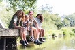 © Sam Edwards/Caia Image - Family sitting on sunny riverside dock