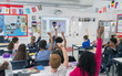 © Robert Daly/Caia Image - Male teacher leading lesson at projection screen in classroom students raising hands