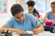 © Robert Daly/Caia Image - Junior high school boy student doing homework in classroom