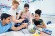 © Robert Daly/Caia Image - Curious junior high school students looking at globe in classroom