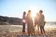 © Trevor Adeline/Caia Image - Women standing in circle on sunny beach during yoga retreat