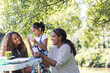 © Sam Edwards/Caia Image - Mother and daughters playing card game at campsite