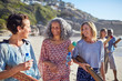 © Trevor Adeline/Caia Image - Women friends yoga mats talking on sunny beach during yoga retreat