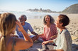 © Trevor Adeline/Caia Image - Friends sitting in circle on sunny beach during yoga retreat