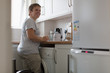 © Martin Barraud/Caia Image - Smiling young woman preparing tea in apartment kitchen