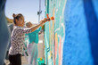 © Trevor Adeline/Caia Image - Women painting vibrant mural on sunny urban wall