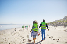 Volunteers Cleaning Up Litter On Sunny, Sandy Beach