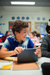 © Paul Bradbury/Caia Image - Happy elementary school boy using digital tablet in classroom