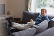 © Martin Barraud/Caia Image - Portrait confident young woman watching TV eating popcorn on sofa feet up on wheelchair