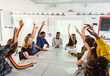 © Chris Ryan/Caia Image - High school students with hands raised in debate class