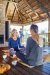 © Trevor Adeline/Caia Image - Women talking and drinking tea in hut during yoga retreat