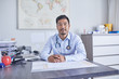 © Trevor Adeline/Caia Image - Portrait confident male doctor working in clinic doctors office