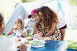 © Sam Edwards/Caia Image - Affectionate daughter hugging father eating lunch at campsite