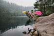 © Jarusha Brown/Caia Image - Playful young couple inflatable rings jumping into remote lake, Squamish, British Columbia, Canada