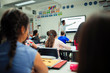 © Paul Bradbury/Caia Image - Junior high school students watching teacher give lesson at projection screen in classroom