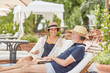 © Trevor Adeline/Caia Image - Mature couple reading books, relaxing on lounge chairs at resort poolside