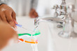© Tom Merton/Caia Image - Close up family rinsing toothbrushes in bathroom sink